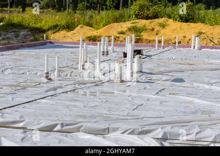 Tubi di scarico in PVC in una nuova casa in preparazione di solette di fondazione per versare calcestruzzo in cantiere. Foto Stock