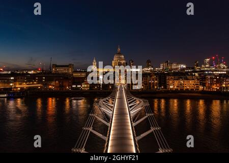 Vista aerea del Millennium Bridge Walkway nella città di Londra con luci e gente che cammina di notte verso la cupola della chiesa Foto Stock