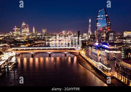 Vista notturna della splendida città di Londra con le architetture urbane ponte a distanza con grattacieli e piccoli edifici intorno all'acqua dell'oceano Foto Stock