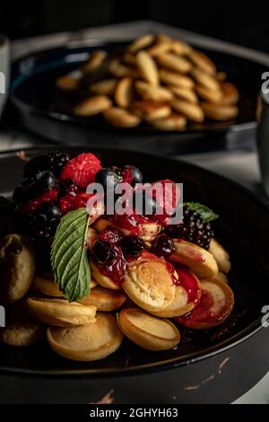 Primo piano di un dolce dolce frittelle ricoperte di marmellata e frutta sul piatto Foto Stock