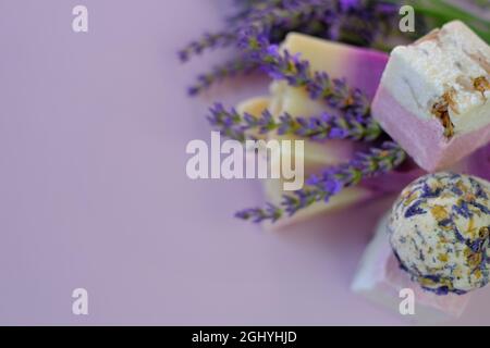 Bagno di lavanda bombe e sapone, fiori di lavanda su un l viola background.Spa e aromaterapia. Cosmetici vegetali biologici con estratto di lavanda. Bellezza Foto Stock