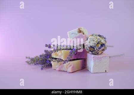 Lavanda bagno bombe e sapone su uno sfondo viola chiaro. Spa e aromaterapia. Cosmetici biologici a base di erbe con estratto di lavanda. Bellezza e relax Foto Stock