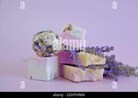 Lavanda bagno bombe e sapone su sfondo viola. Spa e aromaterapia. Cosmetici biologici a base di erbe con estratto di lavanda. Bellezza e relax Foto Stock