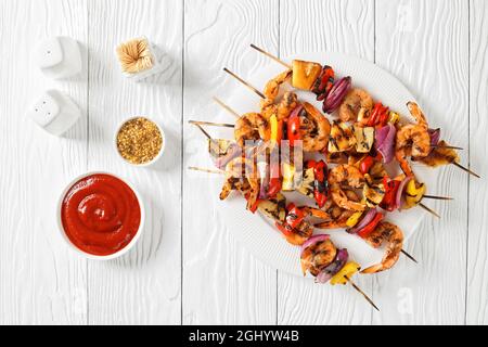 Gamberi Kabobs alla griglia con cipolla rossa, pepe dolce e ananas su un piatto bianco, piatto Foto Stock