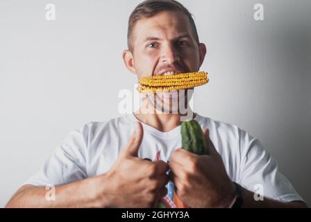 uomo divertente che mangia mais su sfondo bianco Foto Stock