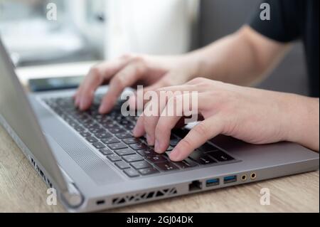 Uomo casual in primo piano con un moderno laptop sulla scrivania. Rimani a casa e lavora da casa Foto Stock