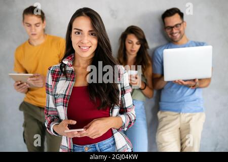 Felici i giovani che lavorano, utilizzando dispositivi digitali. Tecnologia, concetto di persone. Foto Stock