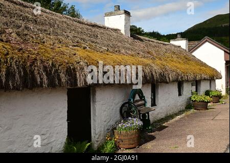 Una vista esterna di un edificio con tetto di paglia nel villaggio montano scozzese di Glencoe Foto Stock
