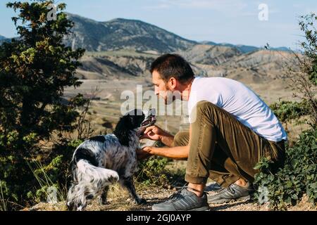 Maschio proprietario di cane spaniel a piedi contro sfondo montagne. Foto Stock