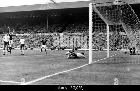 Inghilterra contro Scozia Dave Mackay segna il primo goal della sua squadra mentre il portiere inglese Ron Springett si mette sconfitto sul campo durante la partita internazionale a Wembley. 15 aprile 1961. Foto Stock