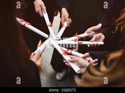 laureati in abiti neri con diplomi o certificati di laurea presso un istituto di istruzione superiore. Foto Stock