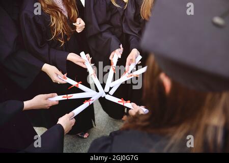 laureati in abiti neri con diplomi o certificati di laurea presso un istituto di istruzione superiore. Foto Stock