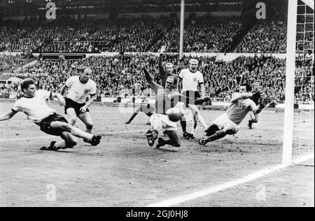 A pochi secondi dalla finale della Coppa del mondo e il lato Wolfgang Weber di West Gemany fa il calcio dopo Gordon Banks in Inghilterra, portiere, per strappare l'eualiserat Wembley Stadium il 30 luglio 1966. Nel tempo extra che seguì, l'Inghilterra segnò due volte per finire con 4-2 vincitori. Anche in questa foto sono il capitano tedesco occidentale Uwe Seeler (seconda a sinistra) Ramon Wilson (camicia scura) d'Inghilterra; dietro Wilson è Moore, il capitano d'Inghilterra; Schnellinger (camicia bianca) e sullo sfondo estrema destra, Jackie Charlton. Appena visto in hte sfondo centro, è George Cohen, l'altro Inghilterra tirare indietro. 30 luglio 1 Foto Stock