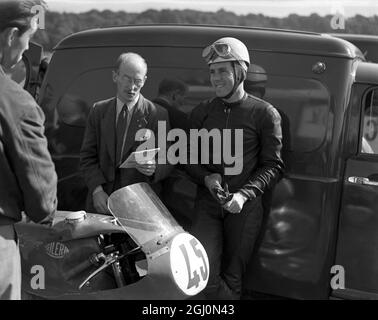 Geoff Duke , campione britannico di motociclette da corsa su strada , si rilassa durante la pratica al circuito di Brands Hatch nel Kent . 24 settembre 1955 Foto Stock