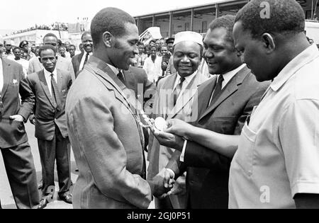 I ministri del Kenya Tom Mboya (secondo da destra) Ministro per la pianificazione economica , e Paul Ngei (destra) , Ministro degli alloggi , esaminano le medaglie d'oro vinte dal runner del Kenya , Kipchoke Keino (sinistra) , ai Giochi del Commonwealth di Kingston , Giamaica . Questa foto è stata scattata il 22 agosto 1966 quando la squadra keniana ha fatto un trionfante ritorno a Nairobi . Keino ha vinto il golf sia per gli eventi Mile che per quelli a cinque miglia. 24 agosto 1966 Foto Stock