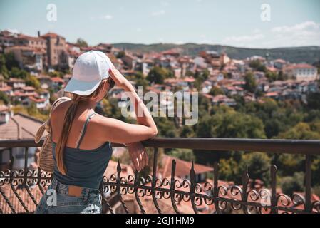 Una ragazza adolescente si erge sulla piattaforma di osservazione sopra la città . Paesaggio estivo della città. Visite turistiche. Foto Stock