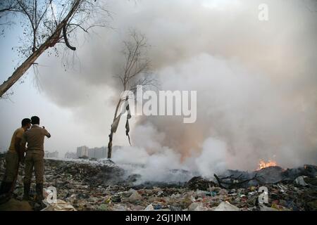 Il personale indiano dei vigili del fuoco cerca di destare il fuoco in un terreno di scarico dei rifiuti a delhi , NCR, India. Foto Stock