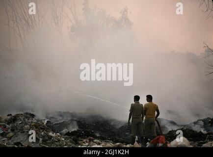 Il personale indiano dei vigili del fuoco cerca di destare il fuoco in un terreno di scarico dei rifiuti a delhi , NCR, India. Foto Stock