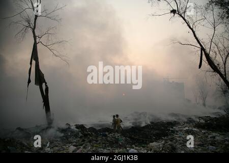 Il personale indiano dei vigili del fuoco cerca di destare il fuoco in un terreno di scarico dei rifiuti a delhi , NCR, India. Foto Stock