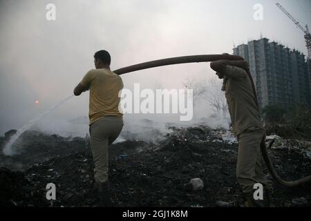 Il personale indiano dei vigili del fuoco cerca di destare il fuoco in un terreno di scarico dei rifiuti a delhi , NCR, India. Foto Stock