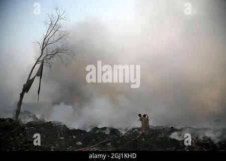 Il personale indiano dei vigili del fuoco cerca di destare il fuoco in un terreno di scarico dei rifiuti a delhi , NCR, India. Foto Stock