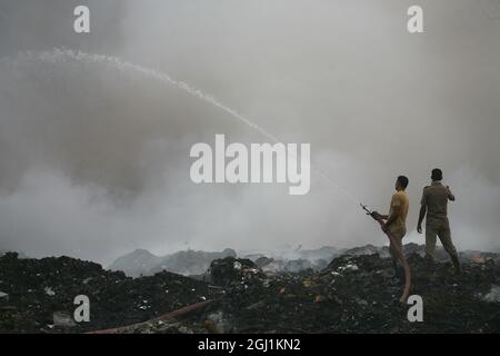 Il personale indiano dei vigili del fuoco cerca di destare il fuoco in un terreno di scarico dei rifiuti a delhi , NCR, India. Foto Stock