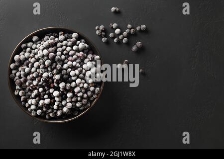 Ribes nero congelato in piastra su sfondo nero con spazio di copia. Vista dall'alto. Foto Stock