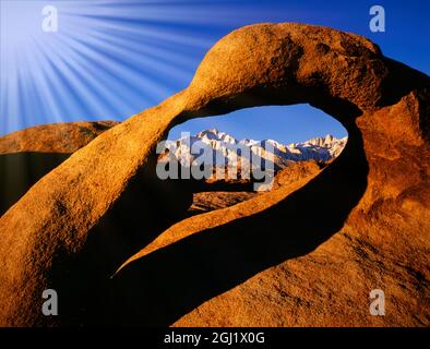 USA, California, Alabama Hills. Raggi del sole e arco di granito che incornicia il picco del pino soleggiato. Foto Stock