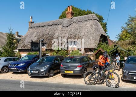 I ciclisti fuori dal Cottage Hotel di paglia nel villaggio di New Forest di Brockenhurst, Hampshire, Inghilterra, Regno Unito Foto Stock