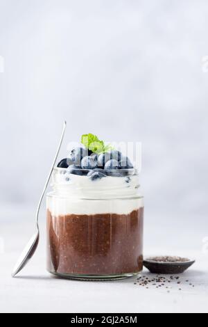 Mousse al cioccolato e yogurt o budino con semi di chia in vaso, con mirtilli freschi Foto Stock