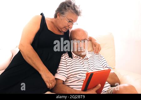 Coppia anziana che utilizza un tablet digitale con un volto sorpreso con uno sfondo bianco e copyspace Foto Stock