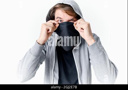 uomo che nasconde il suo volto sotto una maschera con un cappuccio anonimato crimine furto primo piano Foto Stock