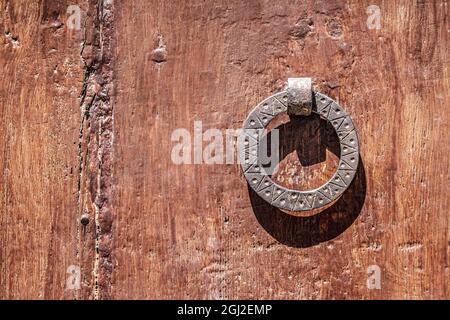 Primo piano di un vecchio batticalcagno metallico su una porta di legno Foto Stock