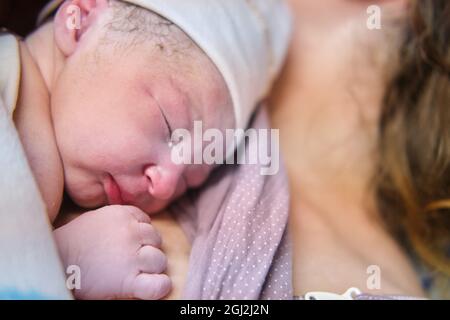 Primo piano della testa di un neonato. Posare il bambino sul petto della madre subito dopo il parto. Una donna che ha dato alla luce un bambino neonato Foto Stock