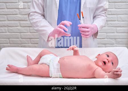 Il medico usa una siringa per iniettare un neonato. Un'infermiera in uniforme si prepara a vaccinare un bambino Foto Stock