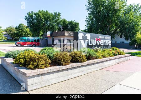 LUVERNE, MN, USA-21 AGOSTO 2021: Cartello monumento per la strada principale di Luverne in un piantatore, con il tram Laverne (autobus) in background. Foto Stock