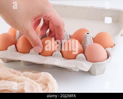 Una donna che prende un uovo di pollo marrone biologico da un cartone. Primo piano. Foto Stock