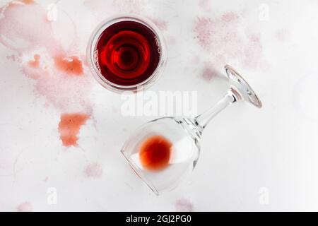 bicchiere di vino rosso e bicchiere capovolto con vino rimasto su sfondo bianco, bevuto e macchiato con vino, vista dall'alto Foto Stock