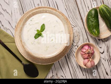 Salsa greca tzatziki su sfondo grigio. Tradizionale raita indiana con cetriolo, yogurt greco e coriandolo, vista dall'alto Foto Stock