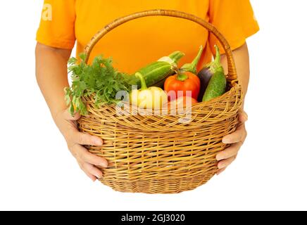 Donna che tiene un cestino di vimini pieno di verdure fresche assortite isolate su bianco Foto Stock