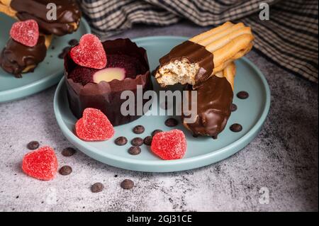 Cupcake di San Valentino. Biscotto digestivo rivestito di cioccolato fondente. Dolce delizioso tartufo da dessert e caramelle a forma di cuore su un piatto. Sfondo scuro wi Foto Stock