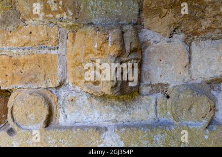 Frammenti della pietra intagliata dall'Abbazia di Hailes incastonati nel muro del cimitero della chiesa di San Pietro vicino a Stanway House, Cotswolds, Inghilterra Foto Stock