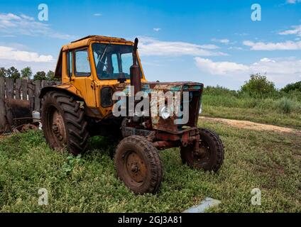 Un vecchio trattore abbandonato in campagna. Macchine agricole. Paesaggio rurale. Foto Stock