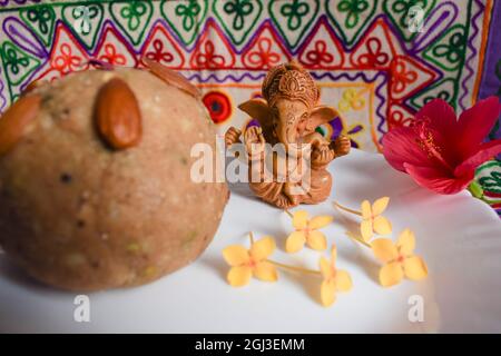 Bella Lord Ganesha piccola cute seduta idol pooja preghiera a casa con motivo ricamo decorazione multicolore sfondo design. Offerta con pra Foto Stock