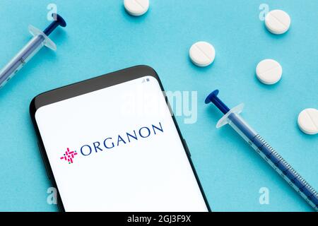 Galizia, Spagna; 8 giugno 2020 : smartphone con logo Organon sullo schermo e pillole e siringa su sfondo blu Foto Stock