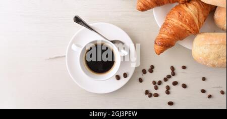 Tazza bianca in porcellana con caffè caldo su tavolo di legno bianco a colazione. Vista dall'alto. Composizione panoramica. Foto Stock