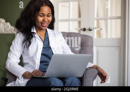 Una dottoressa afro-americana fornisce consulenze di telemedicina attraverso la trasmissione di informazioni mediche attraverso canali di telecomunicazione Foto Stock