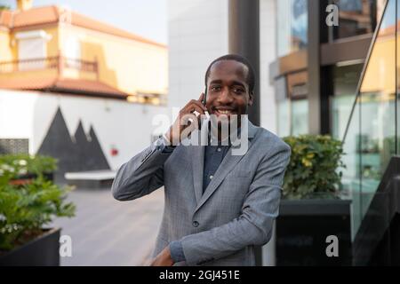 L'uomo d'affari africano effettua una telefonata. Uomo elegante millenario - attività del popolo nero Foto Stock