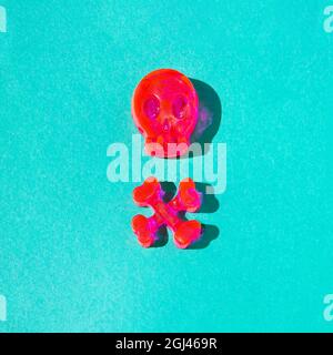 Un cartello di pericolo composto da un cranio e due ossa in rosa neon su sfondo verde pastello. Halloween concetto spooky. Nuovo pericolo retrò, sia spensierato creativ Foto Stock