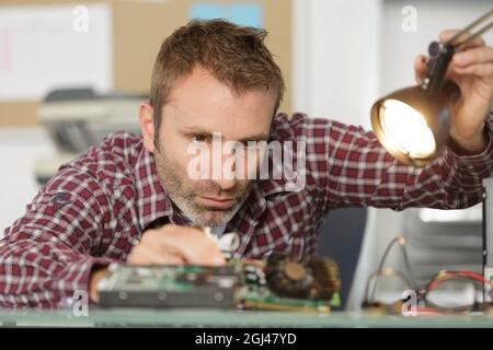 Uomo che fissa il computer mettendo la cpu su socket Foto Stock